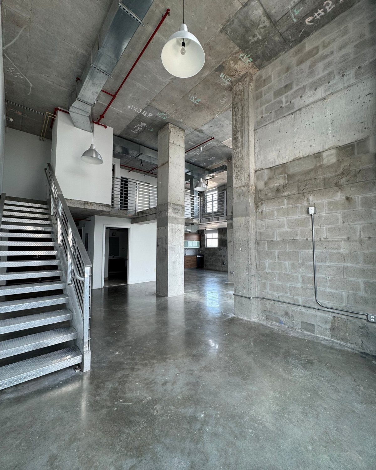 Industrial concrete ceiling with exposed ductwork and piping in a modern open space.
