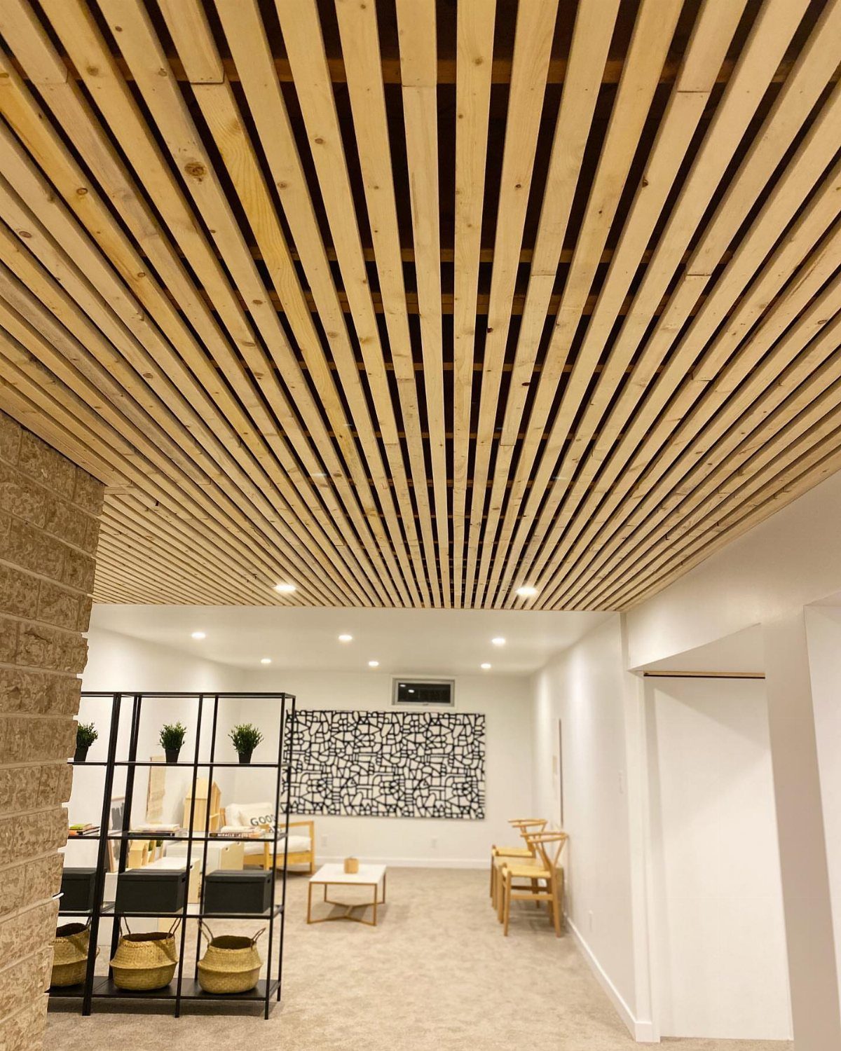 Wooden plank ceiling in a modern room with minimalist furniture and abstract art.