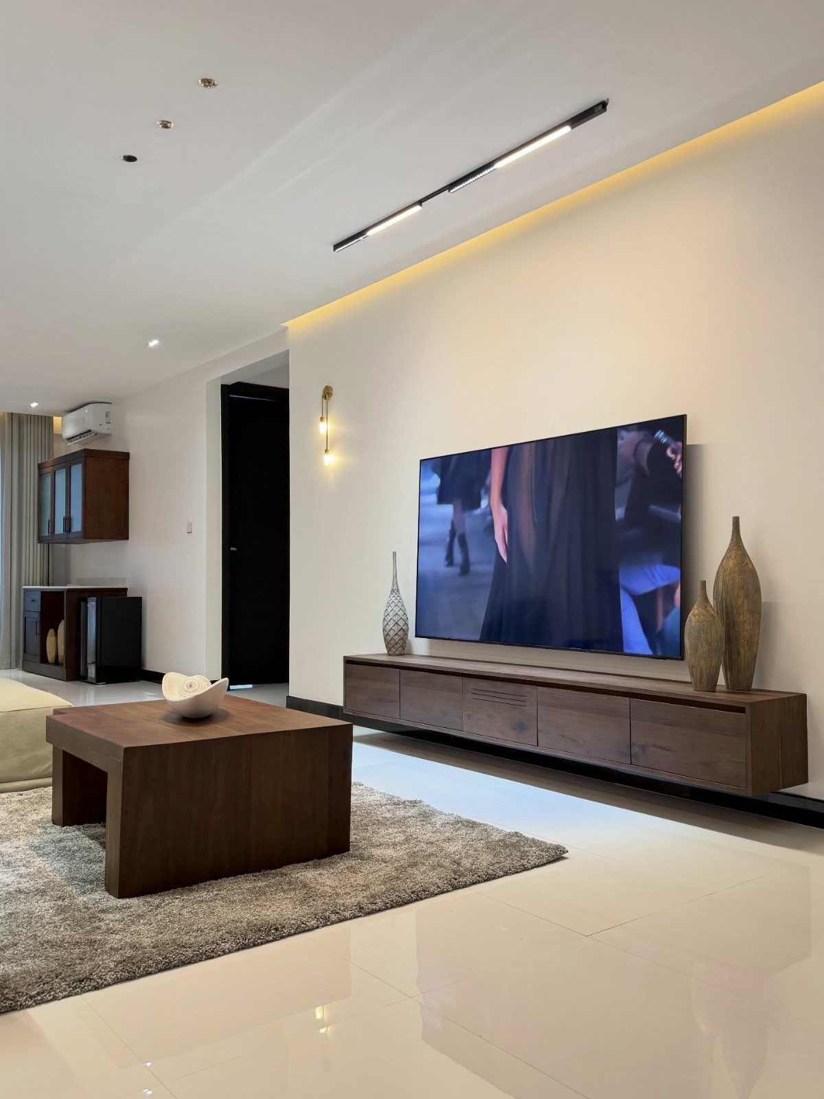 Modern living room with a large TV on a wooden console and neutral decor.