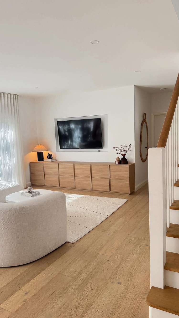Wall-mounted television positioned above a long light-wood buffet in a modern living room