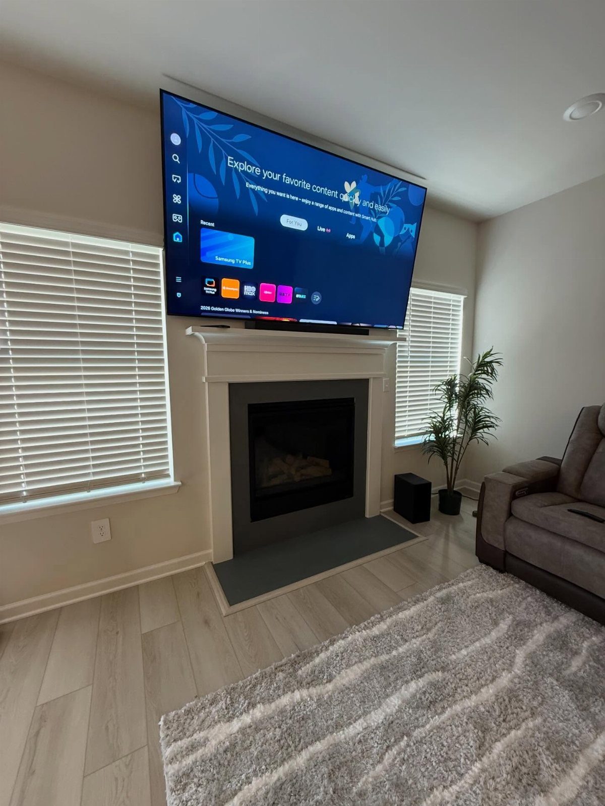 Large flat-screen TV mounted above a white fireplace mantel in a modern living room.