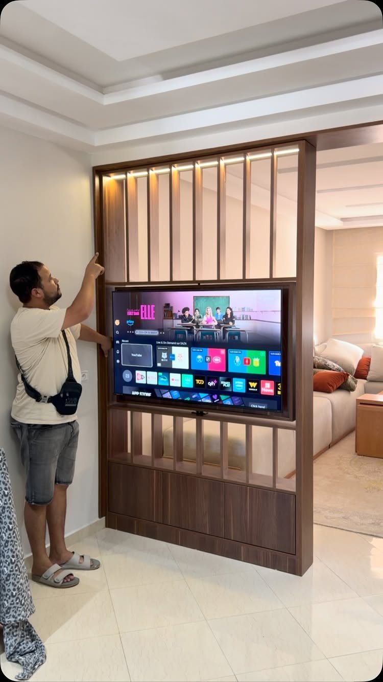 Wooden sliding partition wall with an integrated television screen in a modern home.