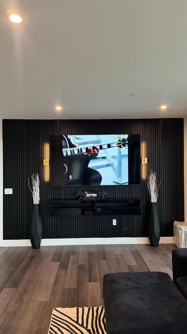 Flat-screen TV mounted on a black slatted feature wall with warm accent lighting.
