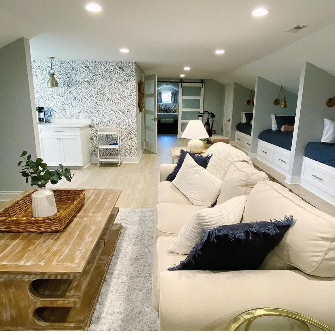 Finished attic living space with white sofa, wooden table, and built-in sleeping nooks.