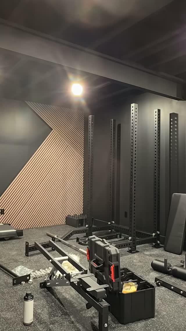 Home gym corner with black power racks and weight bench on rubber flooring.