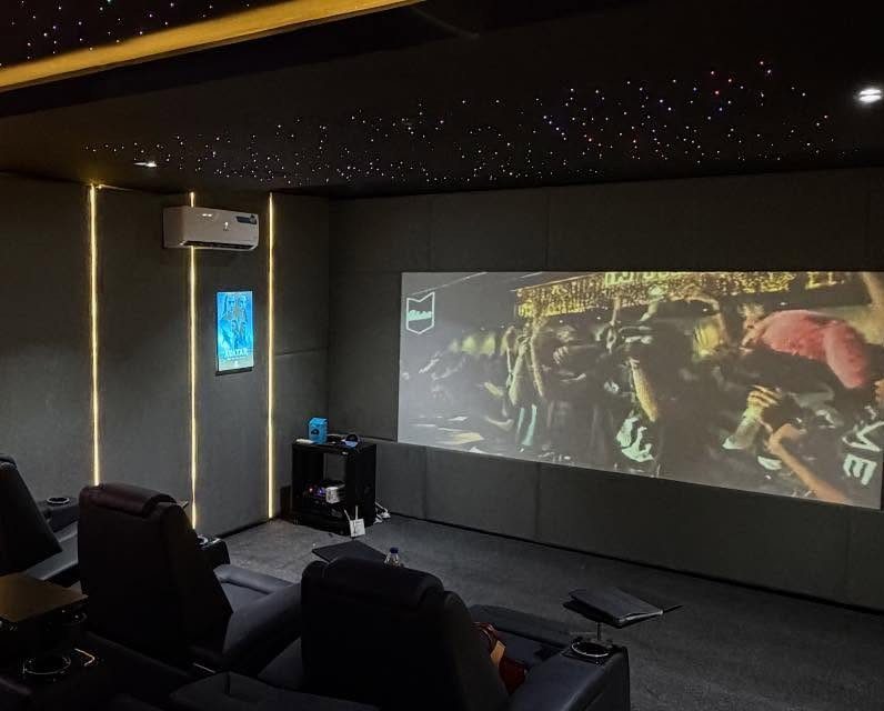 Black reclining theater seats facing a large projection screen in a dark room