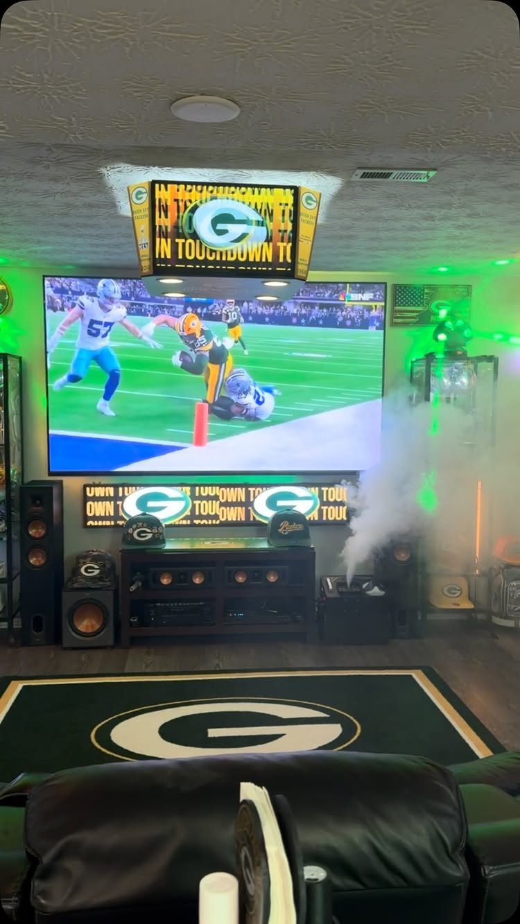 Green Bay Packers themed man cave with large TV and team logo rug