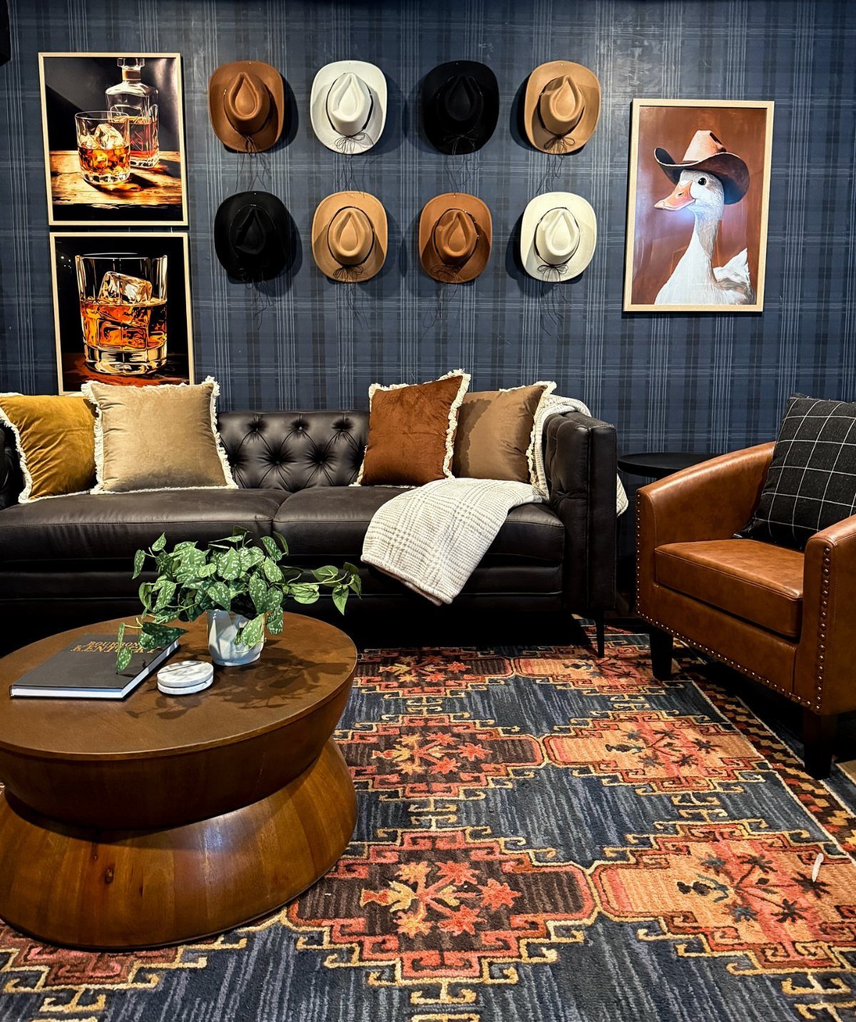 Masculine lounge with leather furniture, cowboy hats on a dark blue wall, and patterned rug.