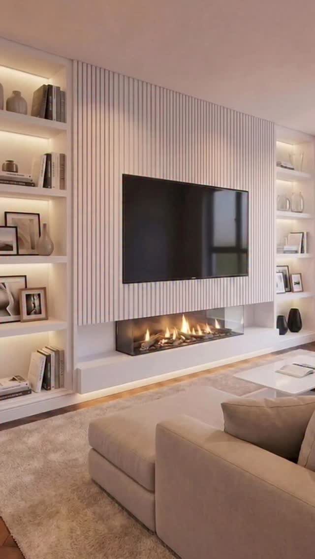 Built-in white wall with bookshelves, a slatted center panel, TV, and linear fireplace.