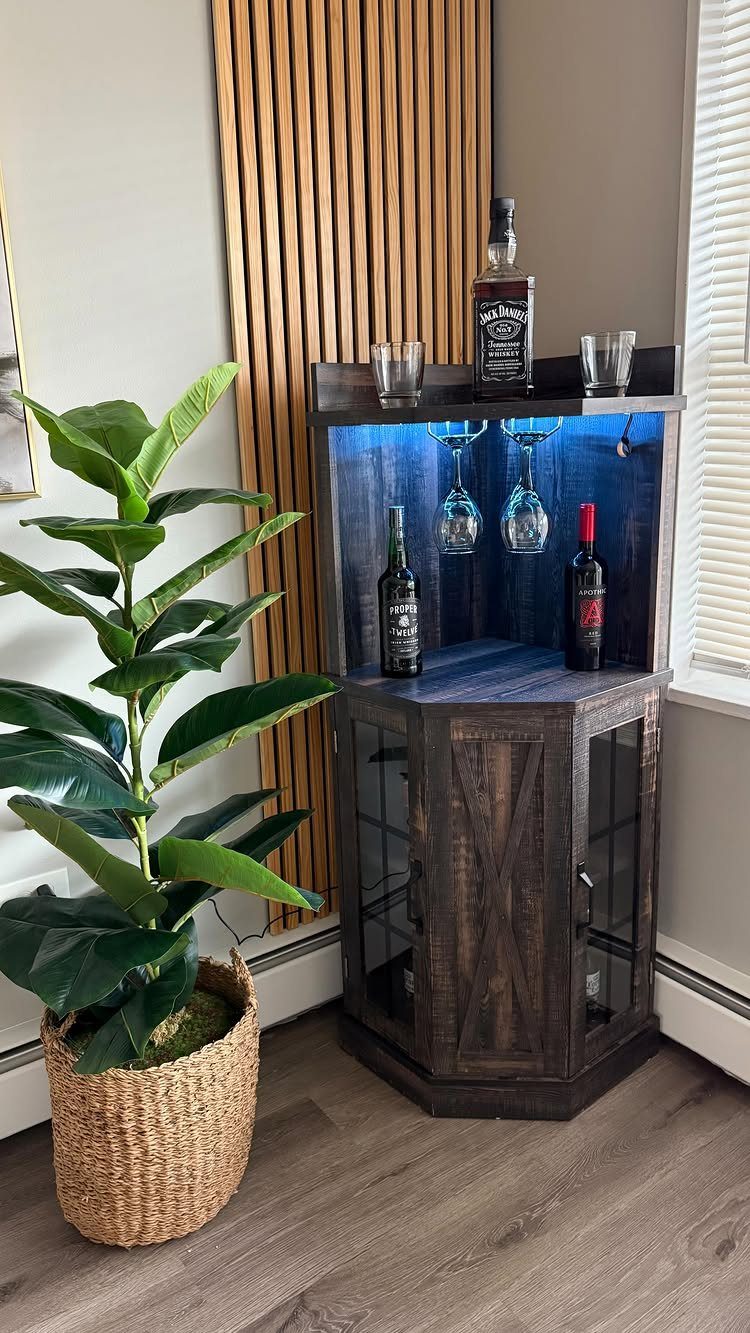 Dark wood corner bar cabinet with blue interior lighting and wine glasses.