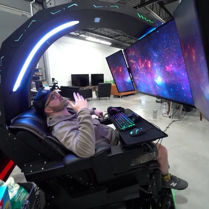 Man in a futuristic gaming pod with multiple monitors showing a space nebula.