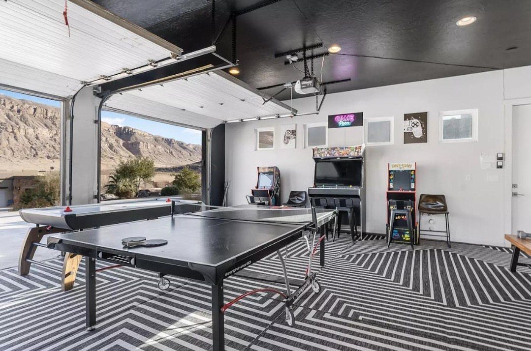 Converted garage game room with ping pong table, pool table, and arcade machines.
