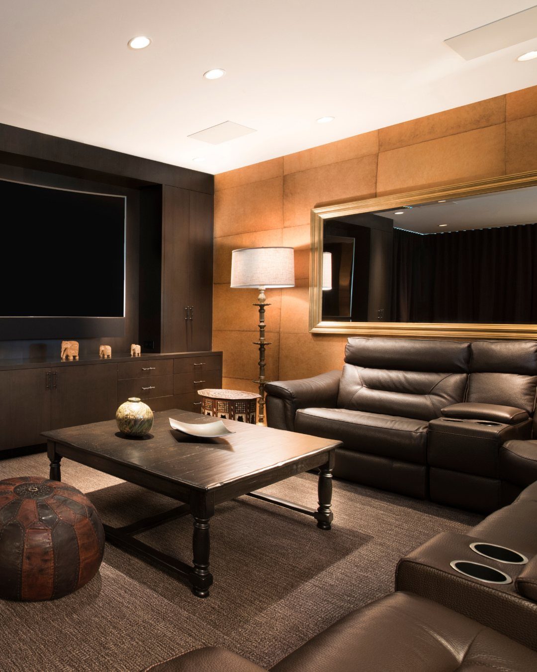 Modern home theater room with leather reclining sofas and a large flat-screen television.