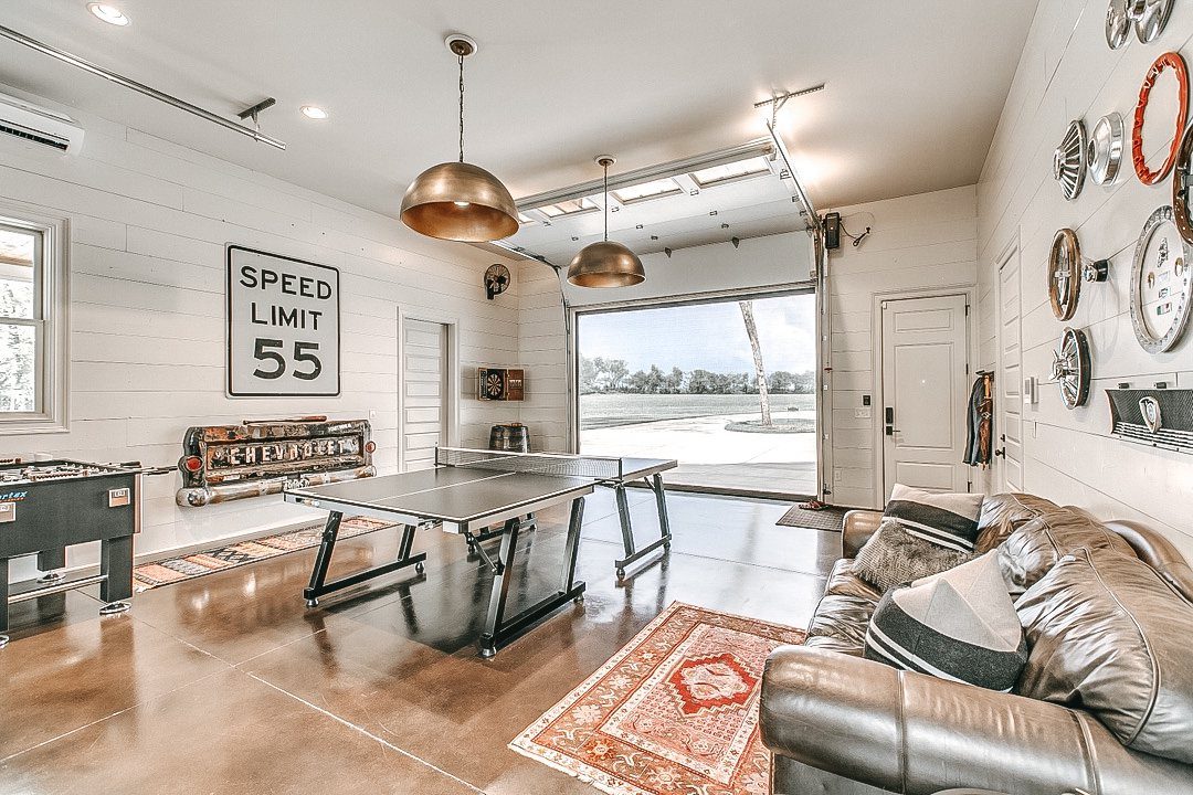 Game room with ping pong table and open garage door leading outdoors.