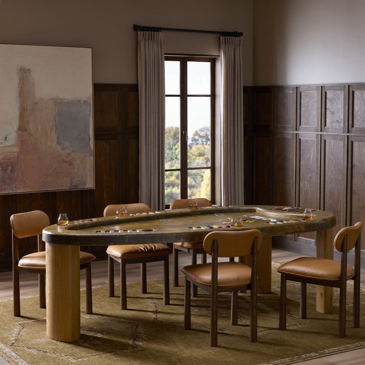 Oval gaming table with leather chairs in a wood-paneled room with abstract art.