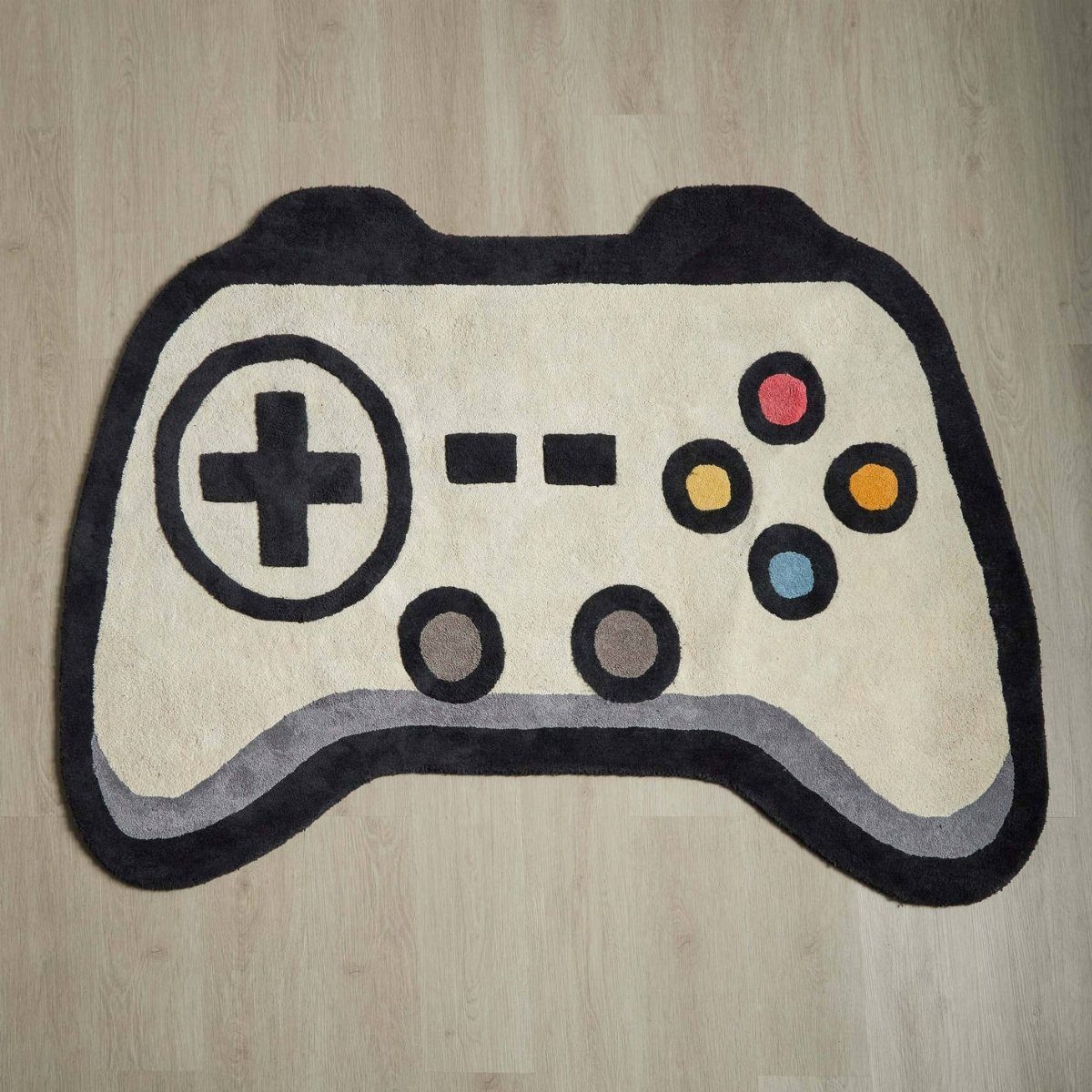 Video game controller shaped rug on a light wooden floor.