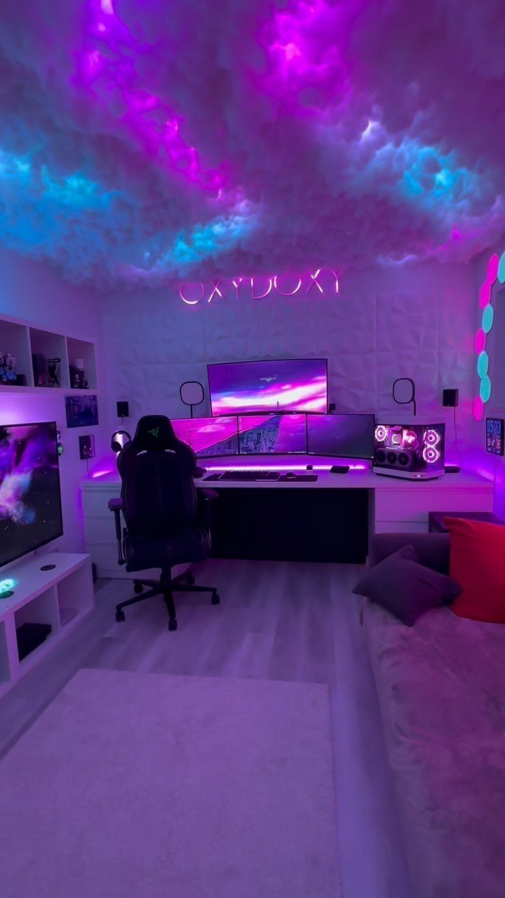 Gaming room with neon purple and blue cloud ceiling, triple monitors, and desk.