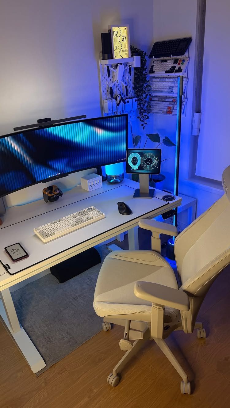 White ergonomic office chair and desk with wide monitor and blue LED lighting.