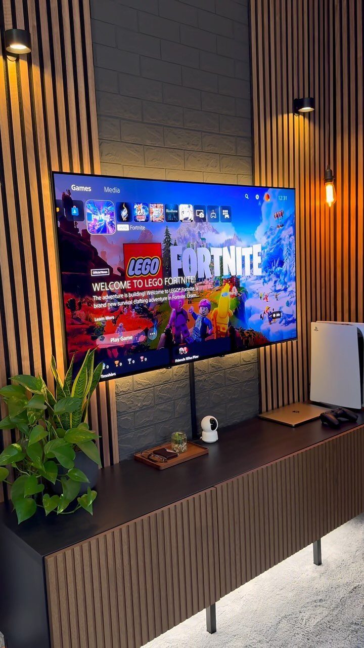 Gaming setup with a large TV showing Fortnite on a wooden cabinet.
