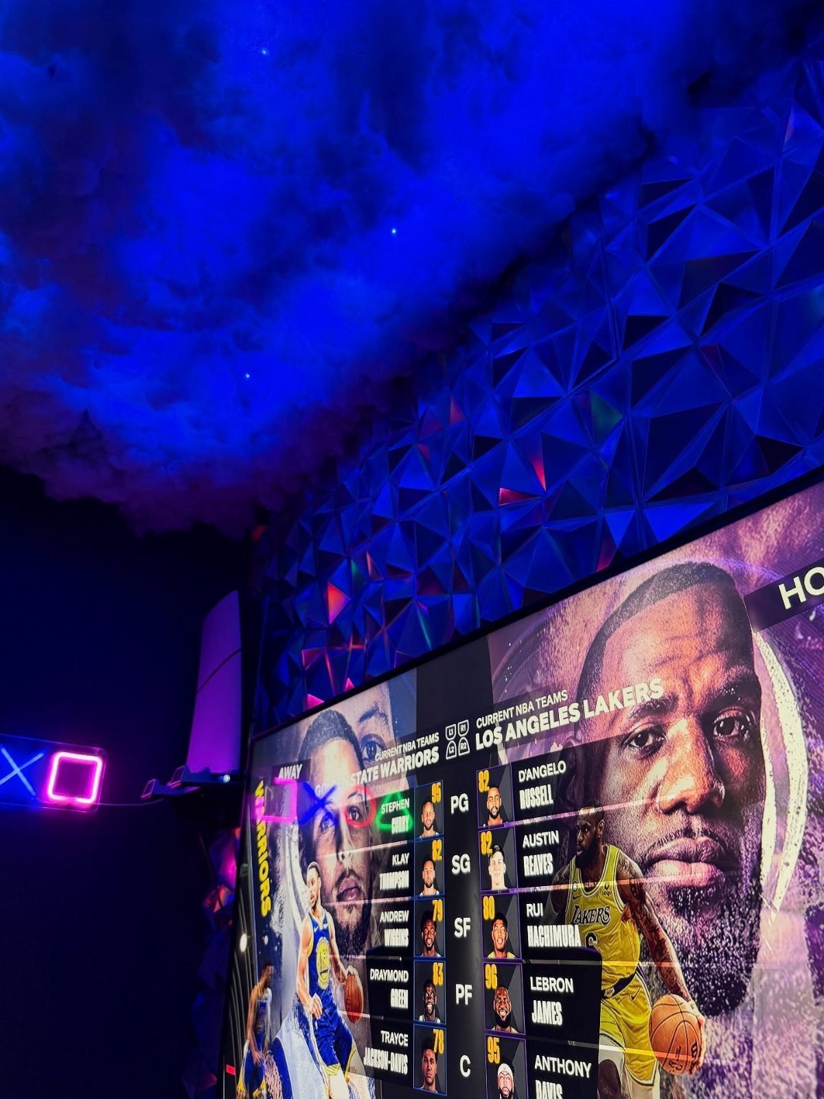 Blue lit room with geometric wall and screen showing basketball player stats.