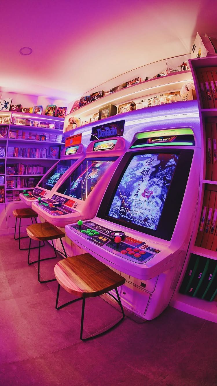 Three white retro arcade game cabinets with wooden stools in a purple neon room.