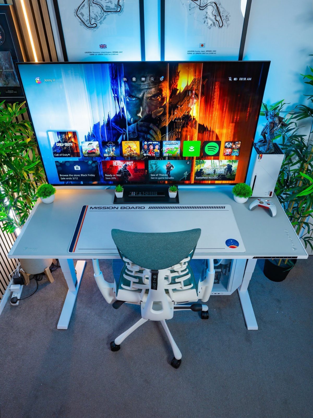 Ultrawide gaming monitor on a white desk with an ergonomic teal office chair.