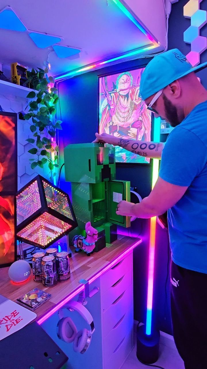 Man opening a green Minecraft mini fridge in a neon lit gaming room