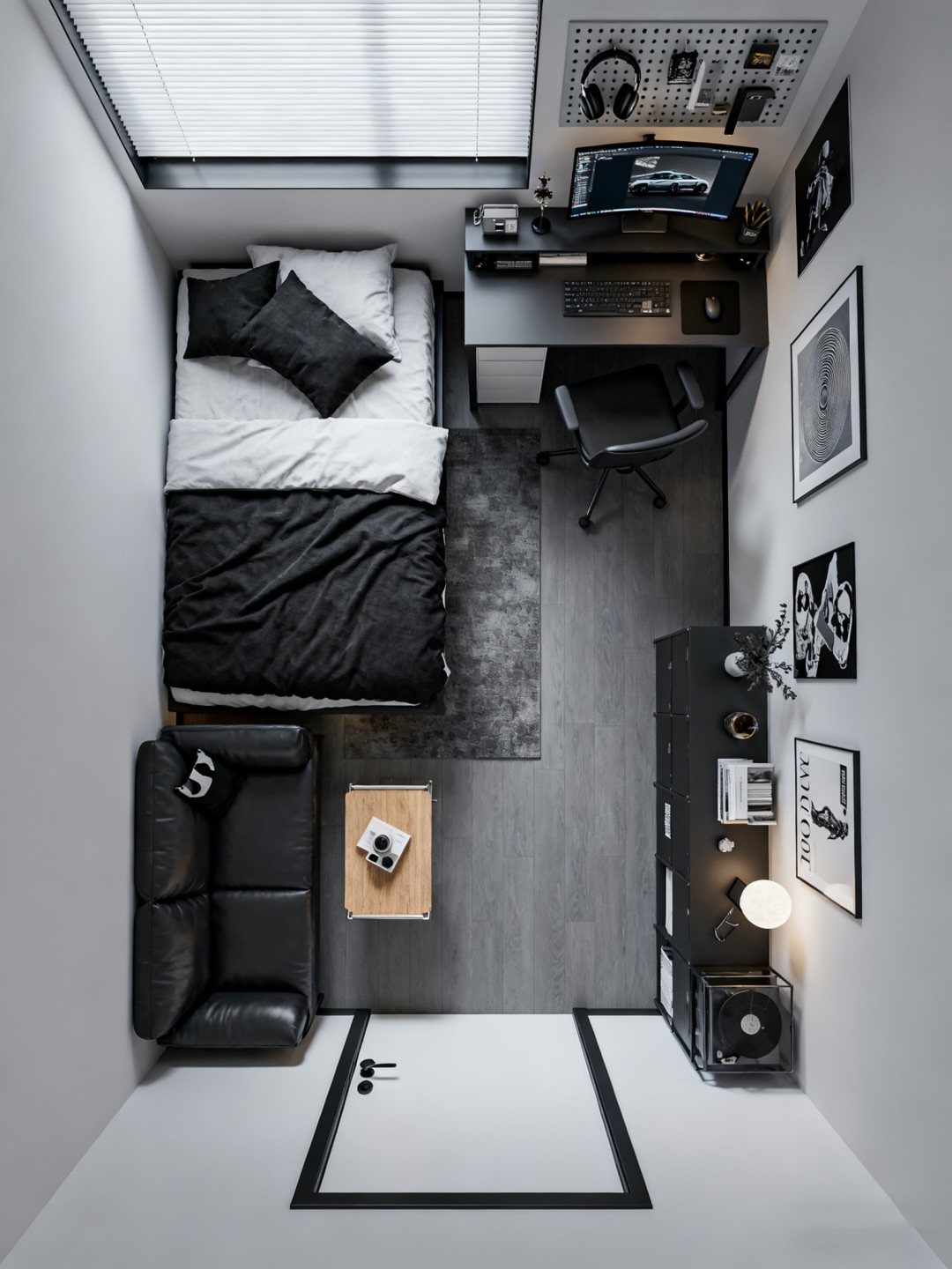 Minimalist black and white bedroom with a gaming desk, bed, and leather sofa.