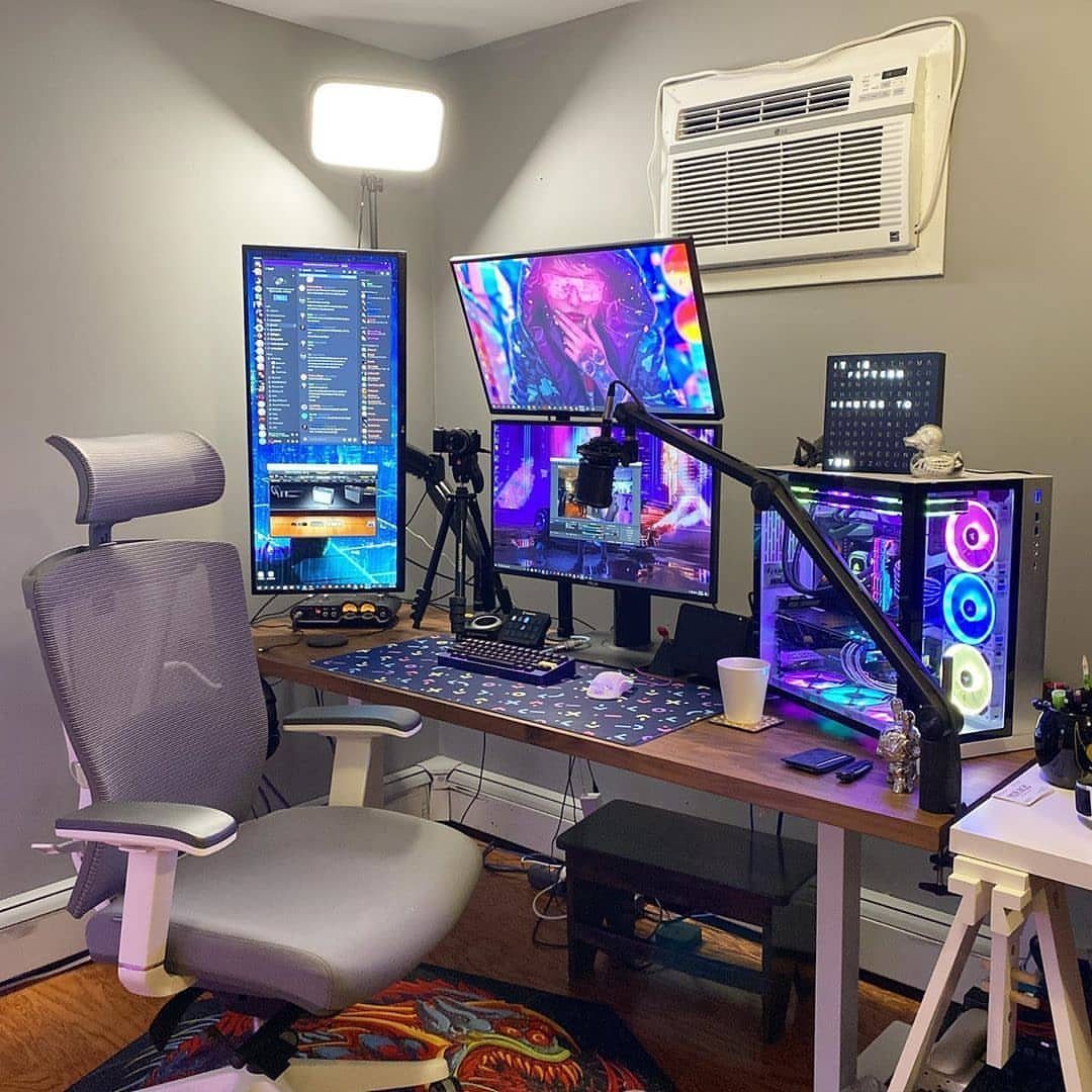 Professional gaming and streaming setup with triple monitors, RGB PC, and boom microphone.