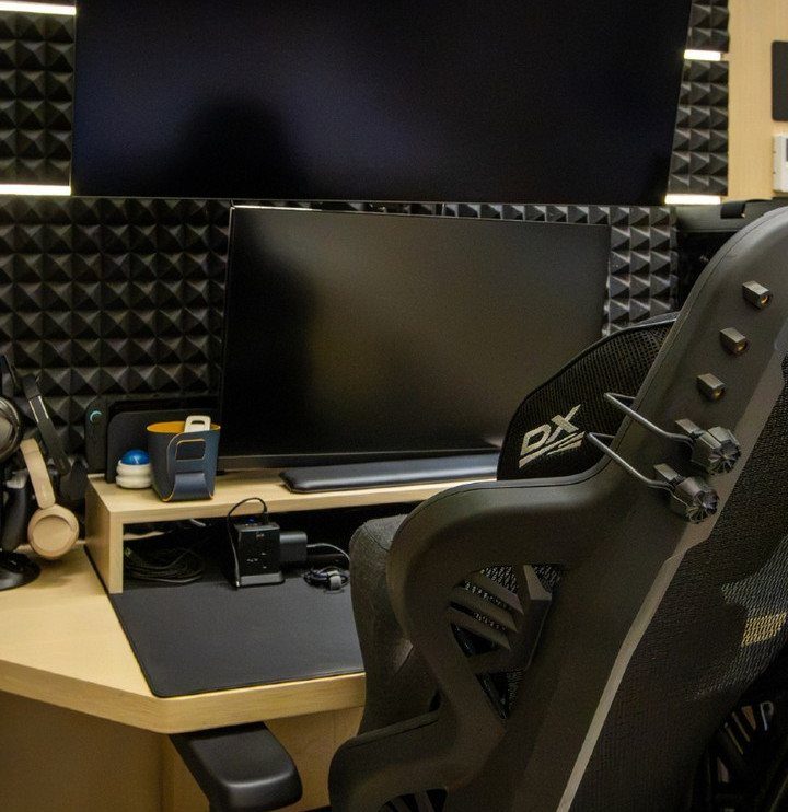 Gaming setup with black acoustic foam soundproofing panels on the wall behind monitors.