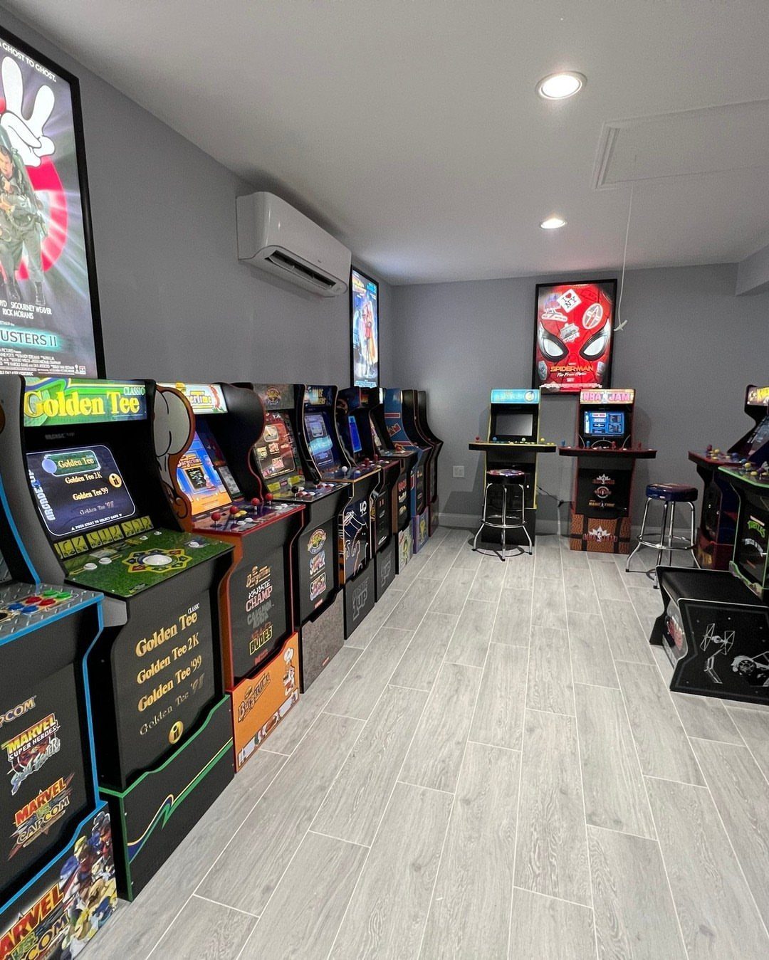 Arcade game machines lined up against a grey wall in a game room.