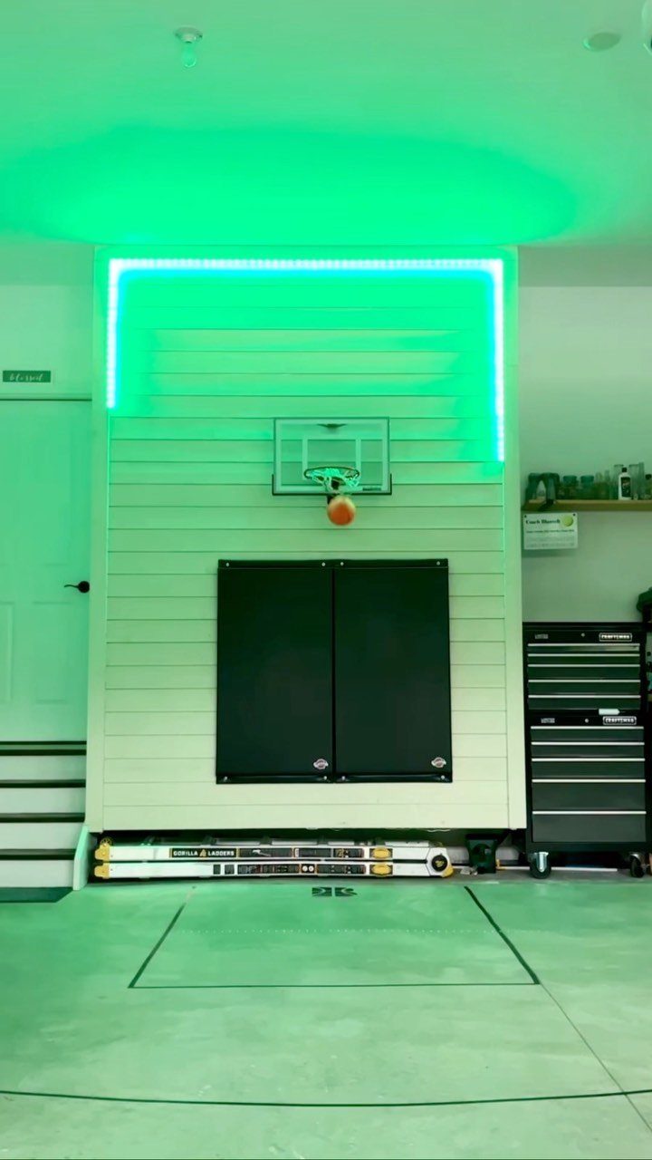 Garage game room with a basketball hoop and bright green LED strip lighting.