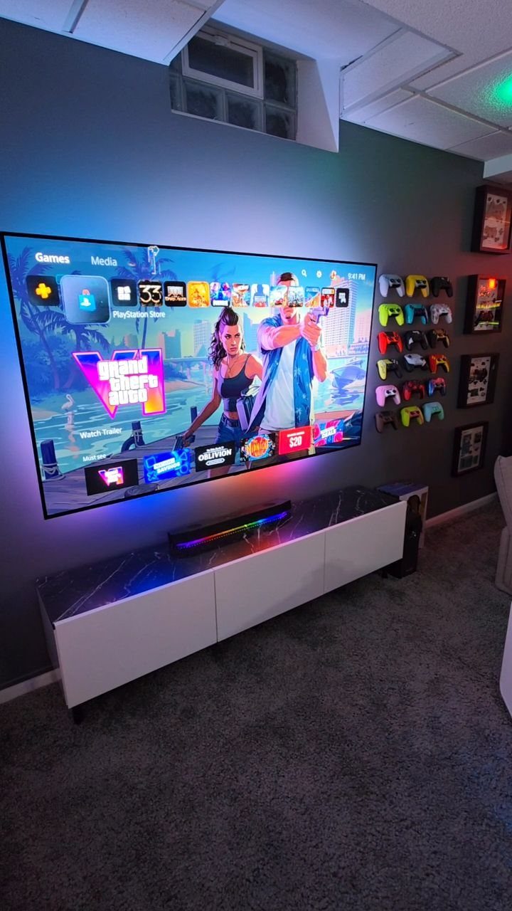 Large television with gaming menu above a white console in a game room