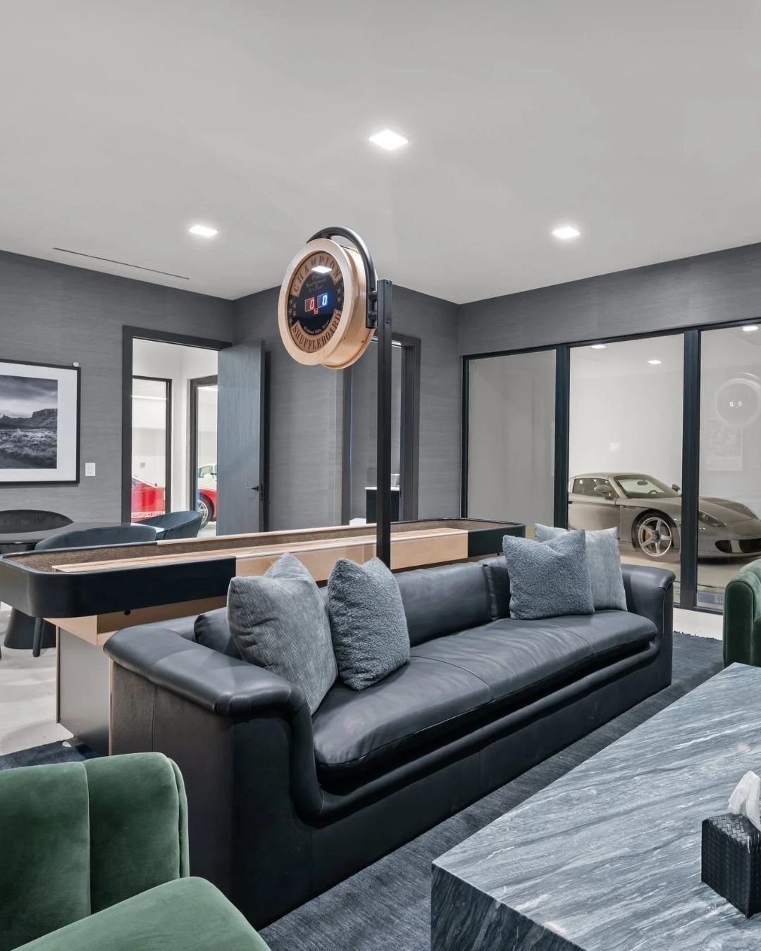 Black leather sofa with grey pillows in a modern garage game room setting