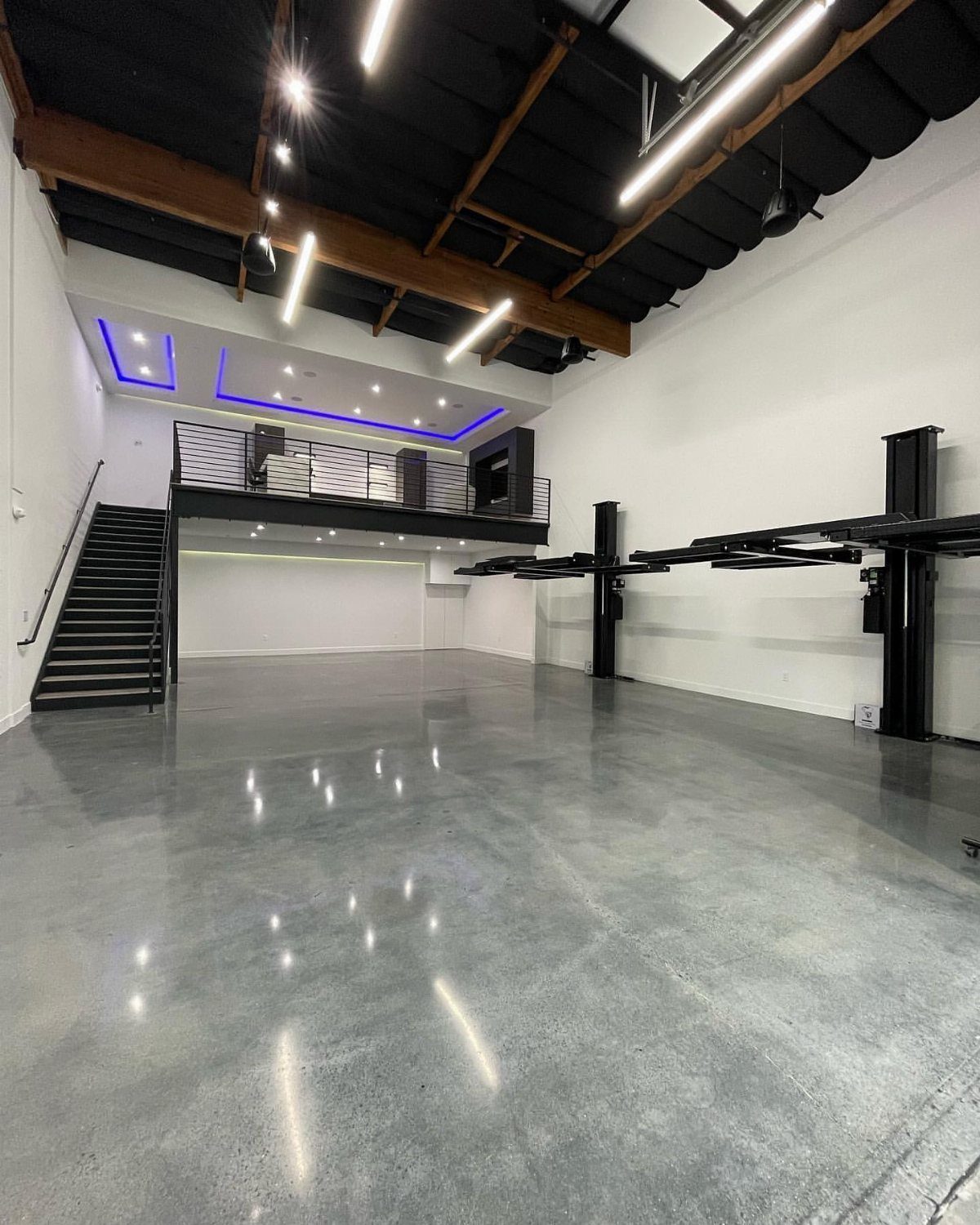 Modern garage interior with polished concrete floors and a small upper loft area.