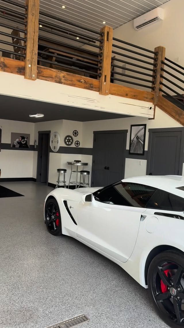 White sports car in a modern garage featuring a wooden loft overhead.