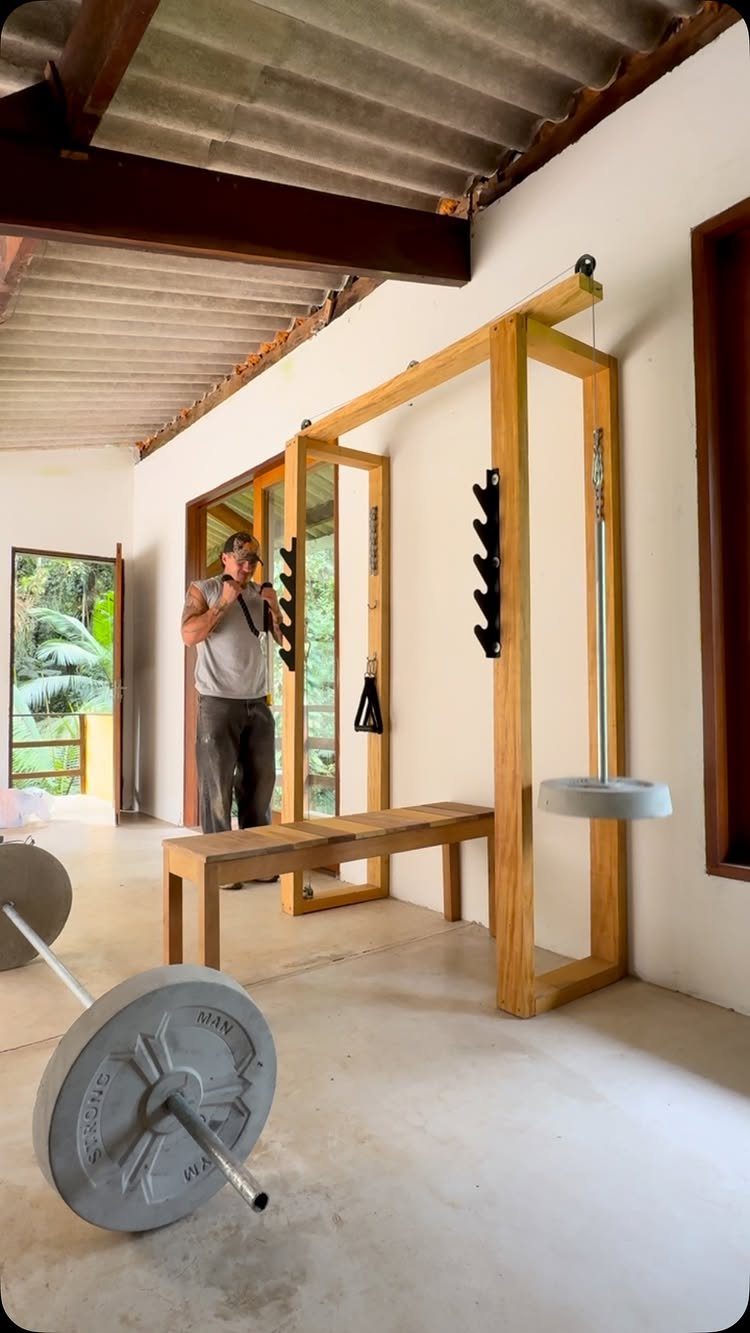 Custom wooden gym rig with weight bench and barbells in a garage space