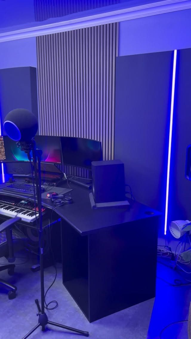 Home music studio with blue lighting and grey acoustic panels on the walls.
