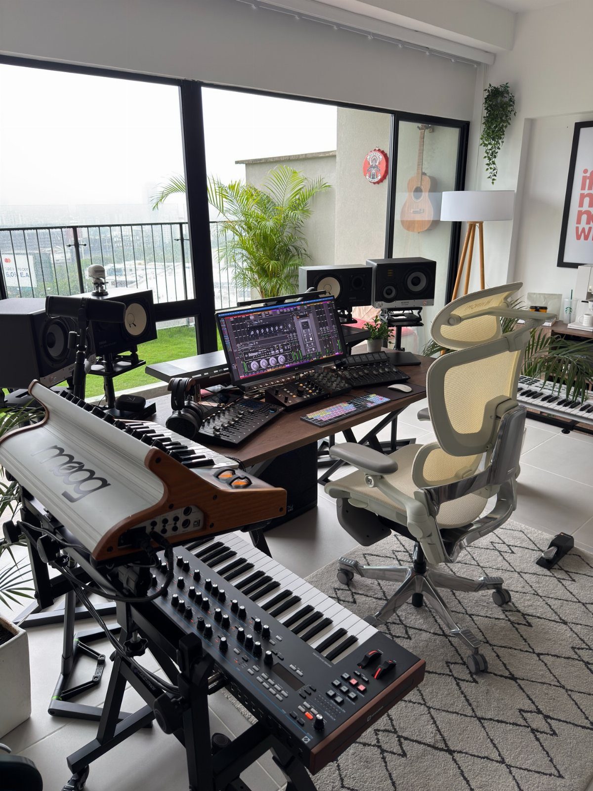 Home music studio with computer monitor, MIDI controllers, keyboards, and studio monitors.