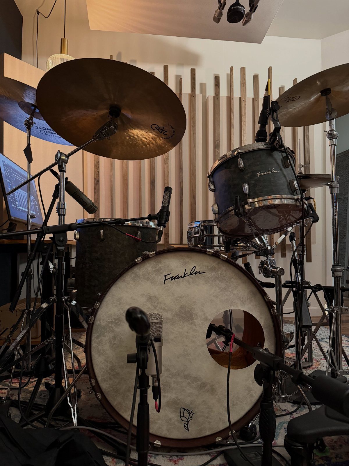 Drum kit with microphones and acoustic wood paneling in a home studio