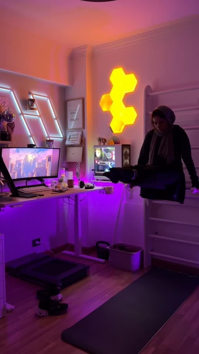 Home office and gym setup with neon lights, computer desk, and exercise equipment.