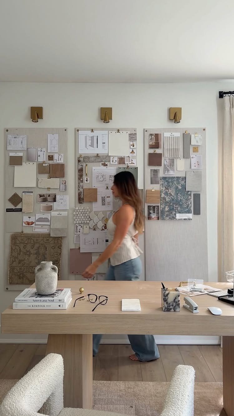 Woman standing before three large design mood boards with fabric and color swatches.
