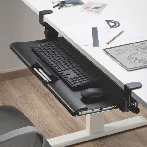 Black sliding keyboard tray with keyboard and mouse under a white office desk