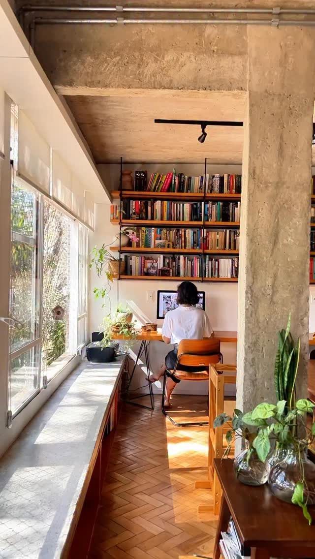 Man working at a desk in front of a large custom wooden bookshelf.
