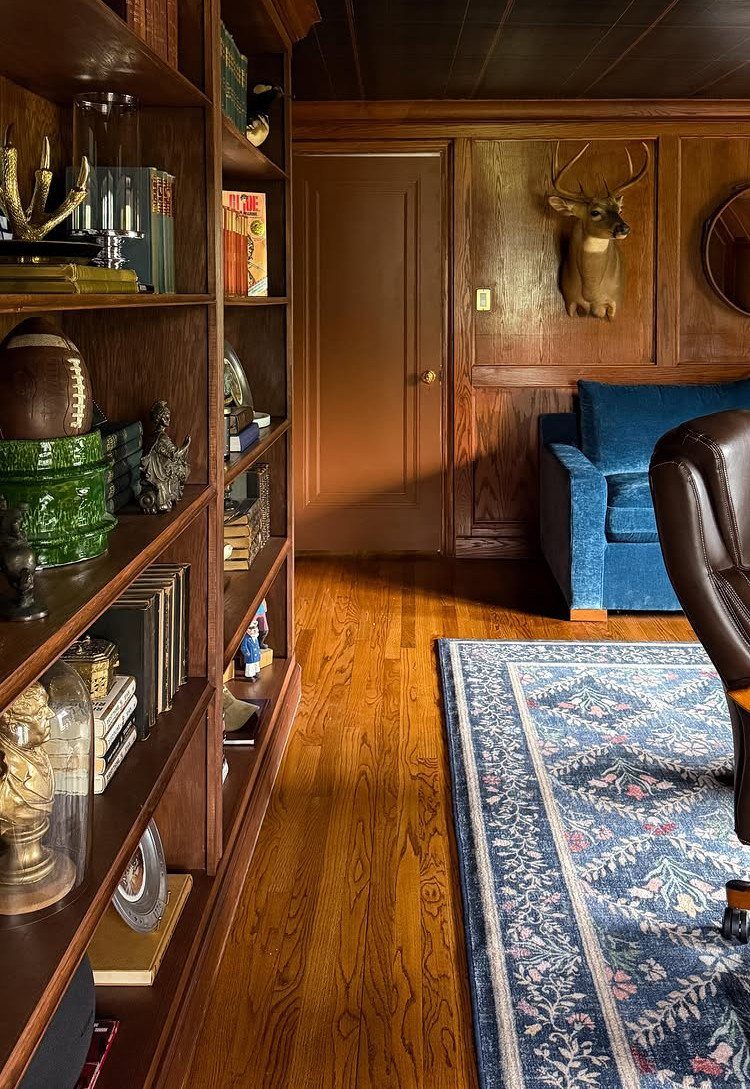 Wooden bookshelf with sports memorabilia and books in a wood-paneled home office.
