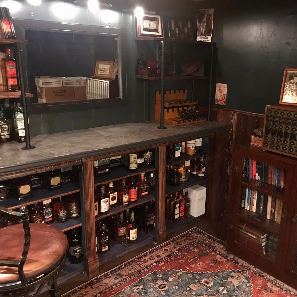Home bar area with liquor bottles on dark shelves and a red patterned rug.