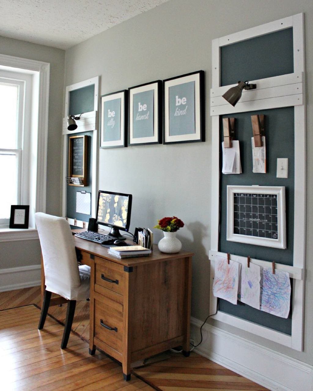 Wooden desk and white chair in an office with vertical wall organizers and art.