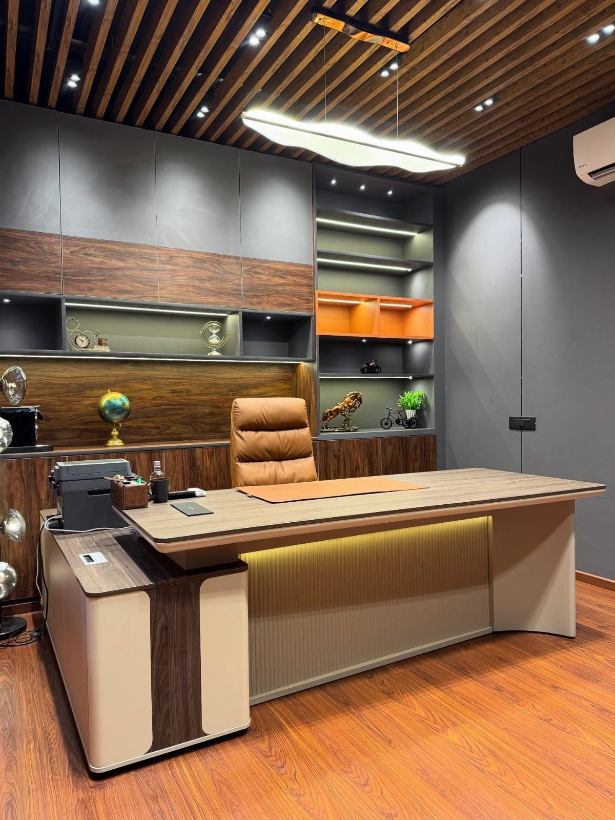 Large wooden desk with a brown leather ergonomic chair in a modern office