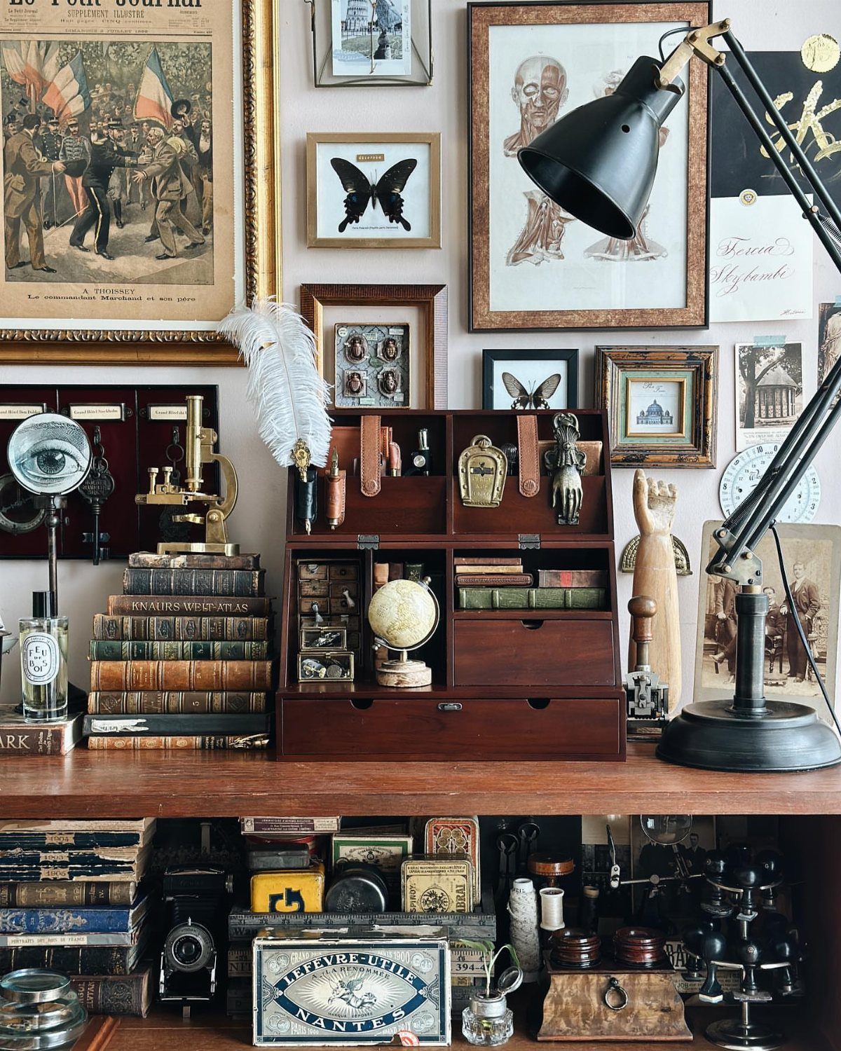Vintage wooden desk with antique books, a globe, and framed wall art.
