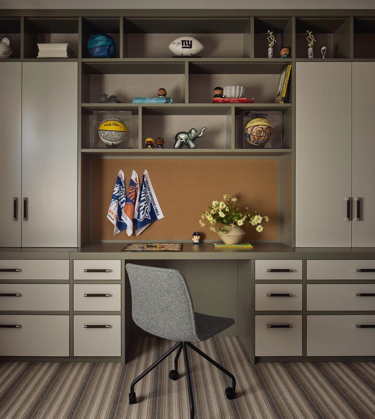 Built-in grey home office desk with extensive vertical shelving and storage cabinets.